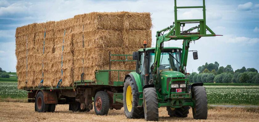 un tracteur et une remorque pleine de bottes de paille